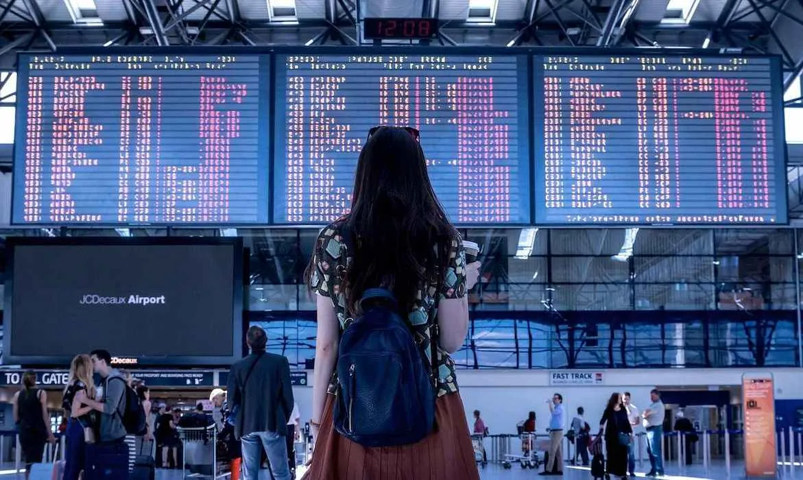 una viaggiatrice davanti al tabellone degli orari dei voli presso l'aeroporto di Phnom Penh
