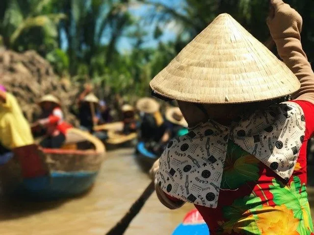 Una donna con cappello conico rema una barca sui canali del Delta del Mekong in Vietnam, durante un itinerario tra Vietnam e Cambogia