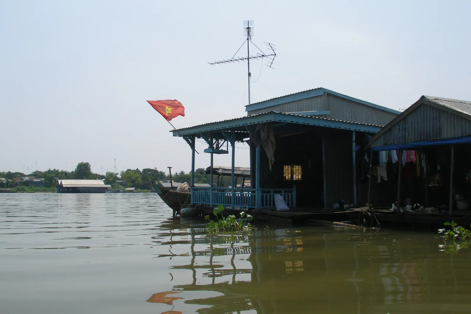 Il Bassac a Chau Doc Case galleggianti con la bandiera vietnamita sul fiume Bassac a Chau Doc, nel Delta del Mekong vietnamito, dalla parte del nuovo valico di Khanh Binh