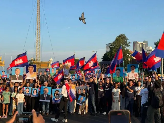 Folla in festa con bandiere della Cambogia e ritratti della famiglia reale durante le celebrazioni a Phnom Penh