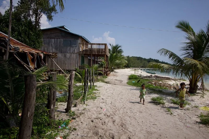 Due bambini giocano con i piedi nella sabbia in un villaggio di pescatori a Koh Rong Due bambini giocano con i piedi nella sabbia in un villaggio di pescatori a Koh Rong