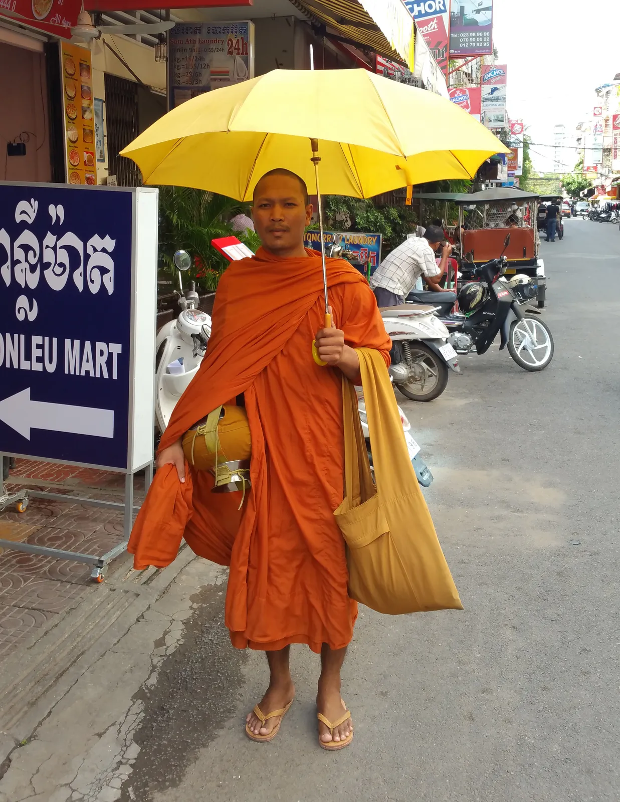 Un monaco buddhista in tunica color zafferano durante la questua mattutina per le strade di Phnom Penh, in Cambogia