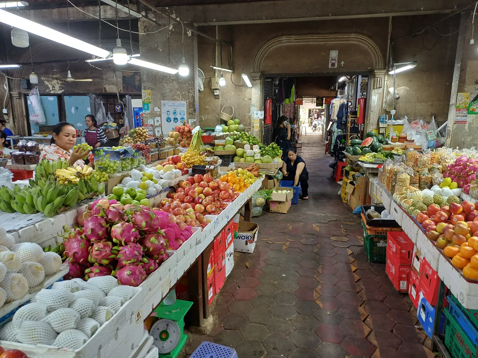 Bancarelle di frutta fresca nel mercato coperto di Siem Reap, tra conversazioni in khmer tra venditori e clienti