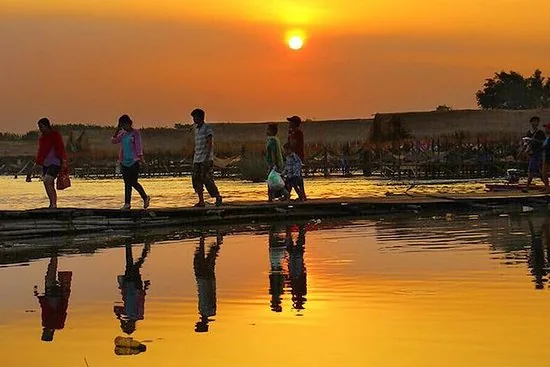 persone che camminano su una lingua di sabbia durante un rosso tramonto a kratie