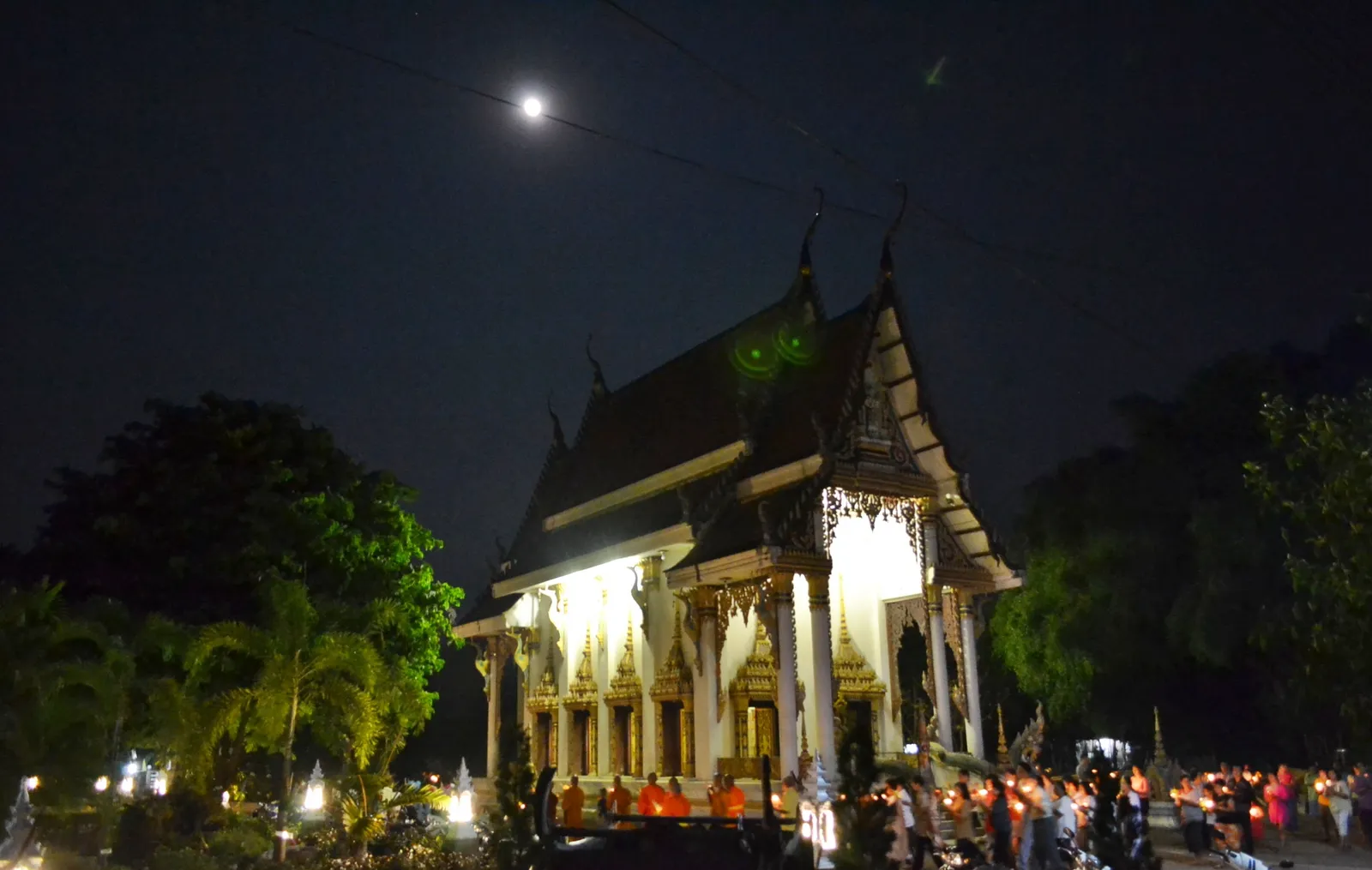 Processione a lume di candela sotto la luna piena durante la festa di Makha Bucha, intorno ad un tempio buddhista