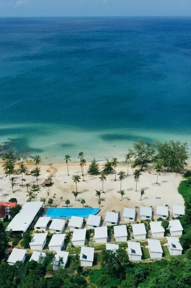 Resort con bungalow sulla spiaggia di un'isola della Cambogia Vista aerea di un resort con bungalow bianchi e piscina sulla spiaggia di un'isola cambogiana