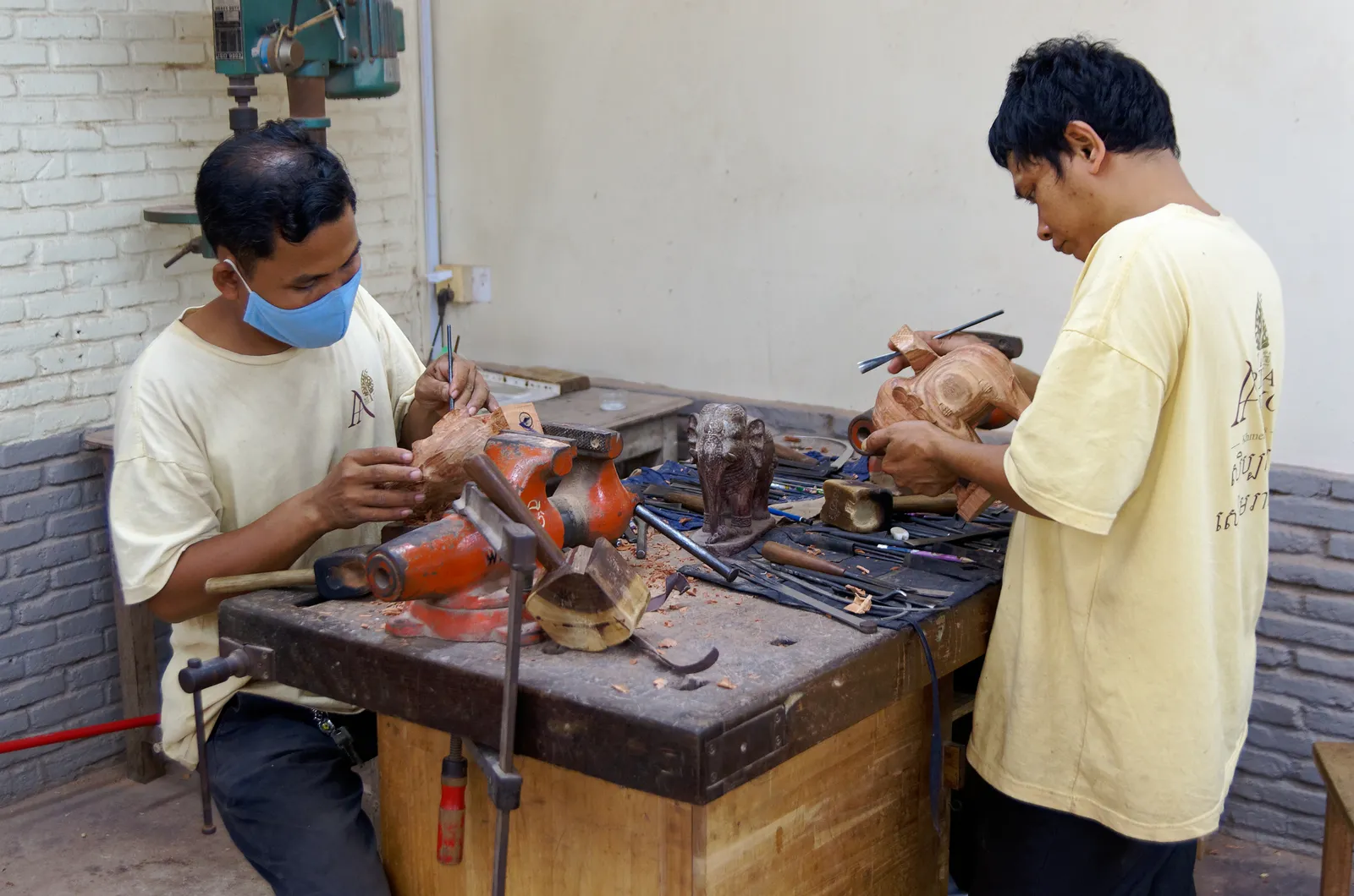 Scultori all'opera a Artisans Angkor Scultori khmer al lavoro su figure in legno nell'atelier di Artisans Angkor a Siem Reap: scalpelli e morsetti sul banco