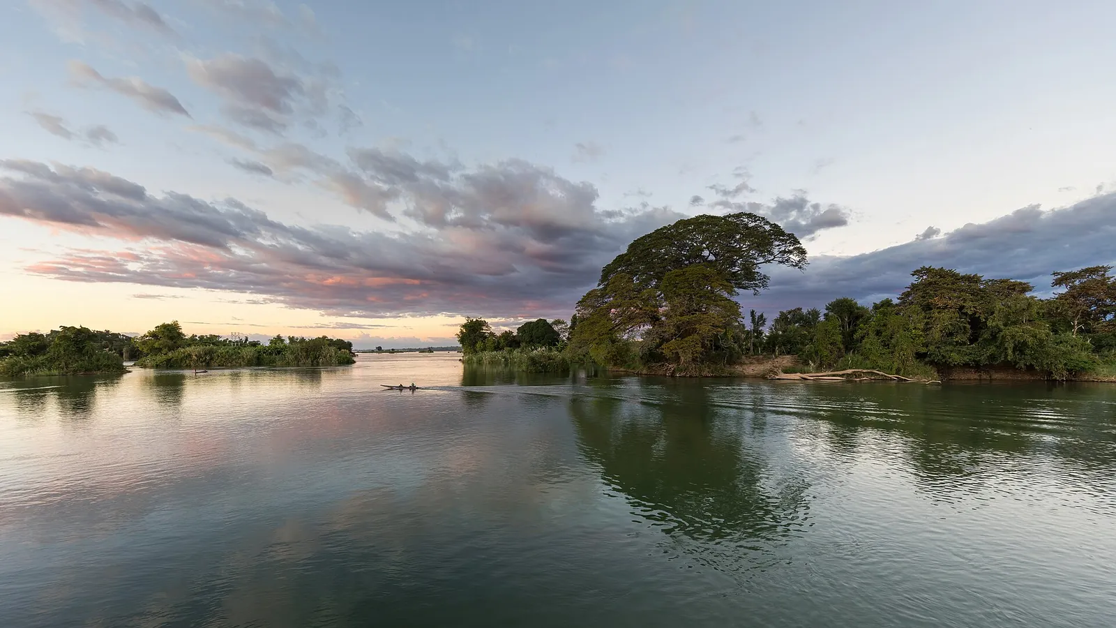 Una piroga solca il Mekong al tramonto tra le isole di Don Det e Don Khon a Si Phan Don in Laos, vicino alla frontiera terrestre con la Cambogia
