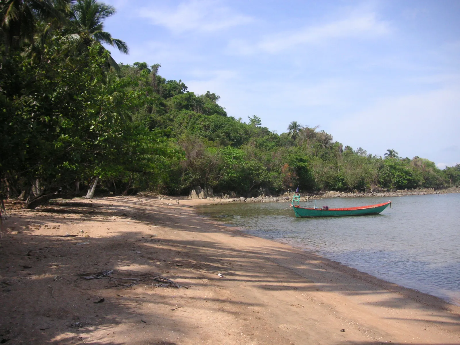 La spiaggia sabbiosa dell'isola di Koh Tonsay (Rabbit Island) con una barca ormeggiata davanti alla vegetazione tropicale, Cambogia