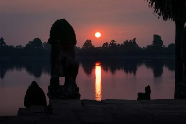 Srah Srang, l'alba tranquilla sul bacino reale Il leone di pietra in silhouette e il sole che sorge sul bacino reale di Srah Srang ad Angkor, Cambogia