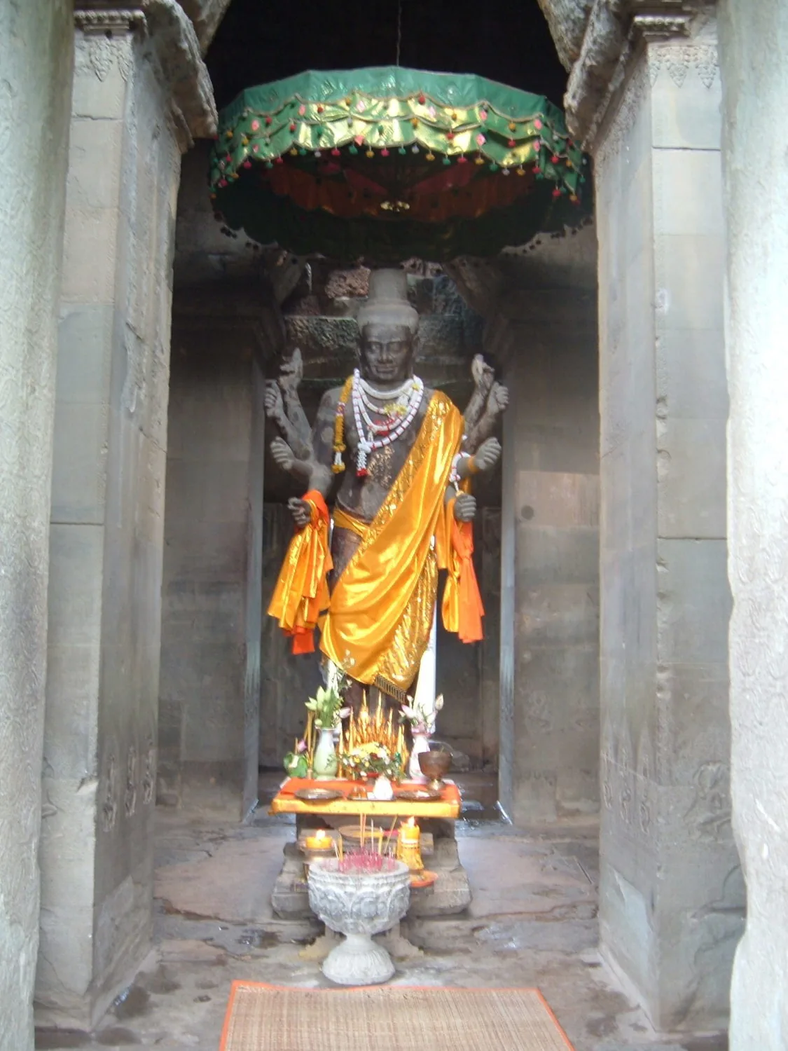 statua di Buddha con abiti gialli sotto ombrello verde, Angkor