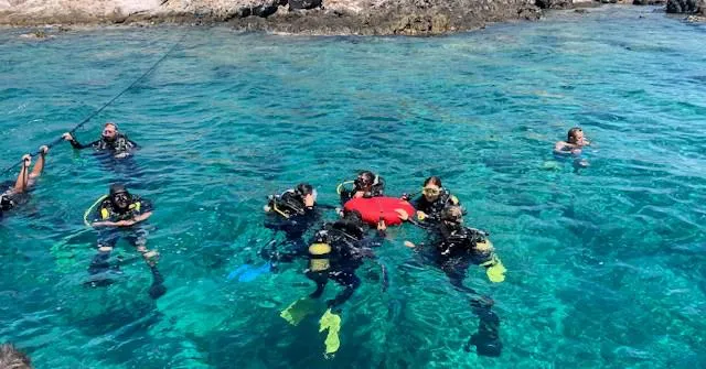 Gruppo di sub in cerchio durante un'esercitazione in mare cristallino, tra le immersioni di diving in Cambogia