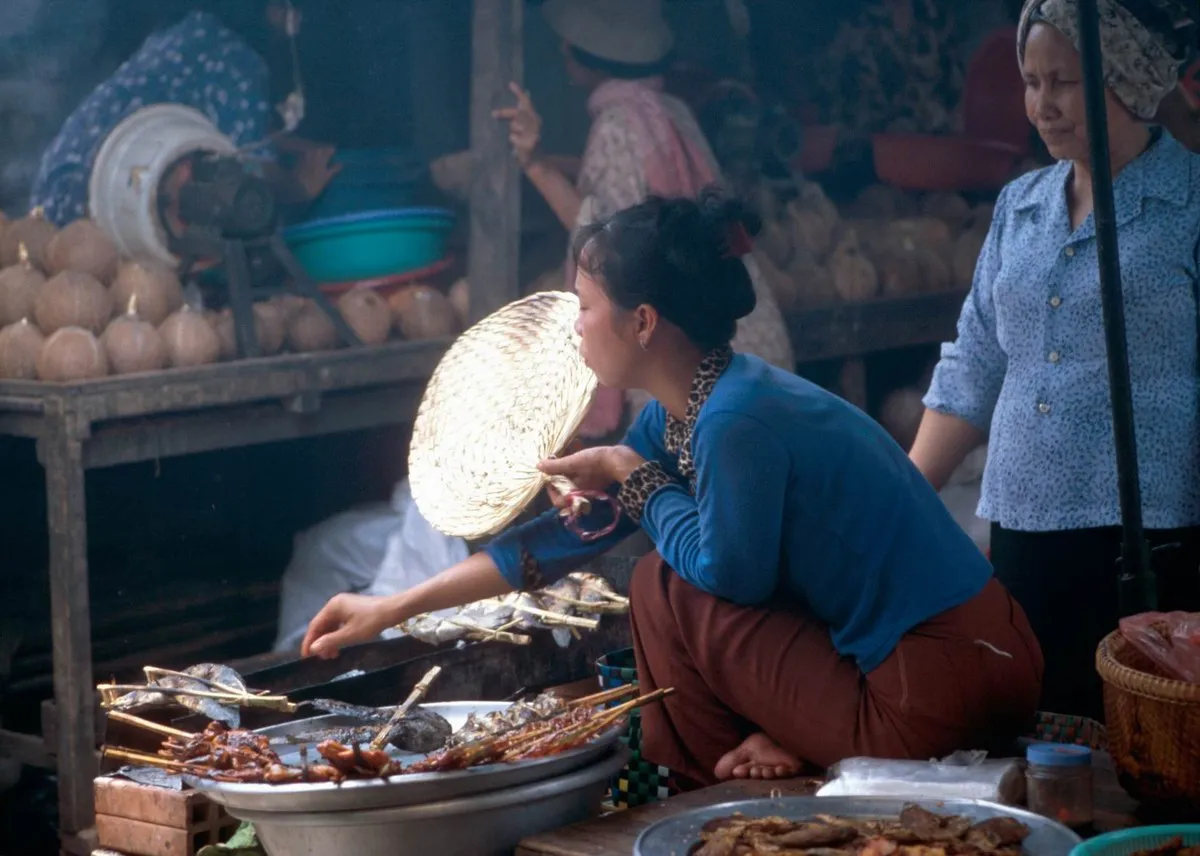 Un venditore di street food in Cambogia Un venditore di street food cucina al banco in una strada della Cambogia, con pentole e verdure fresche
