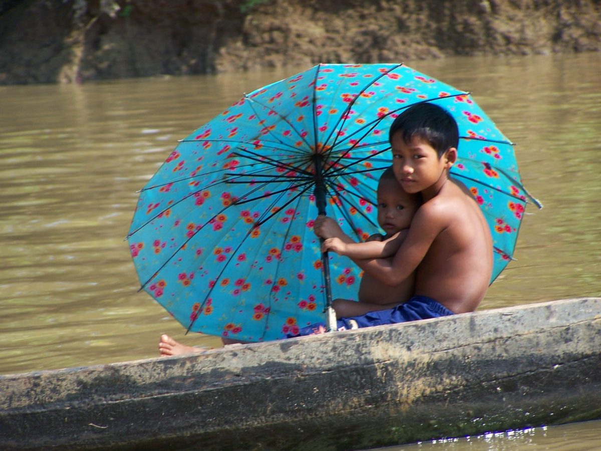 Bambini con ombrello sul fiume